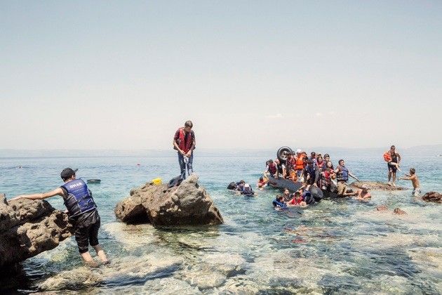 2015. Lesvos. Greece. A boat carrying Syrians and people of other nationalities is helped to land by two local famers. The boat had started to leak, forcing a small group of people to swim to the shore.  